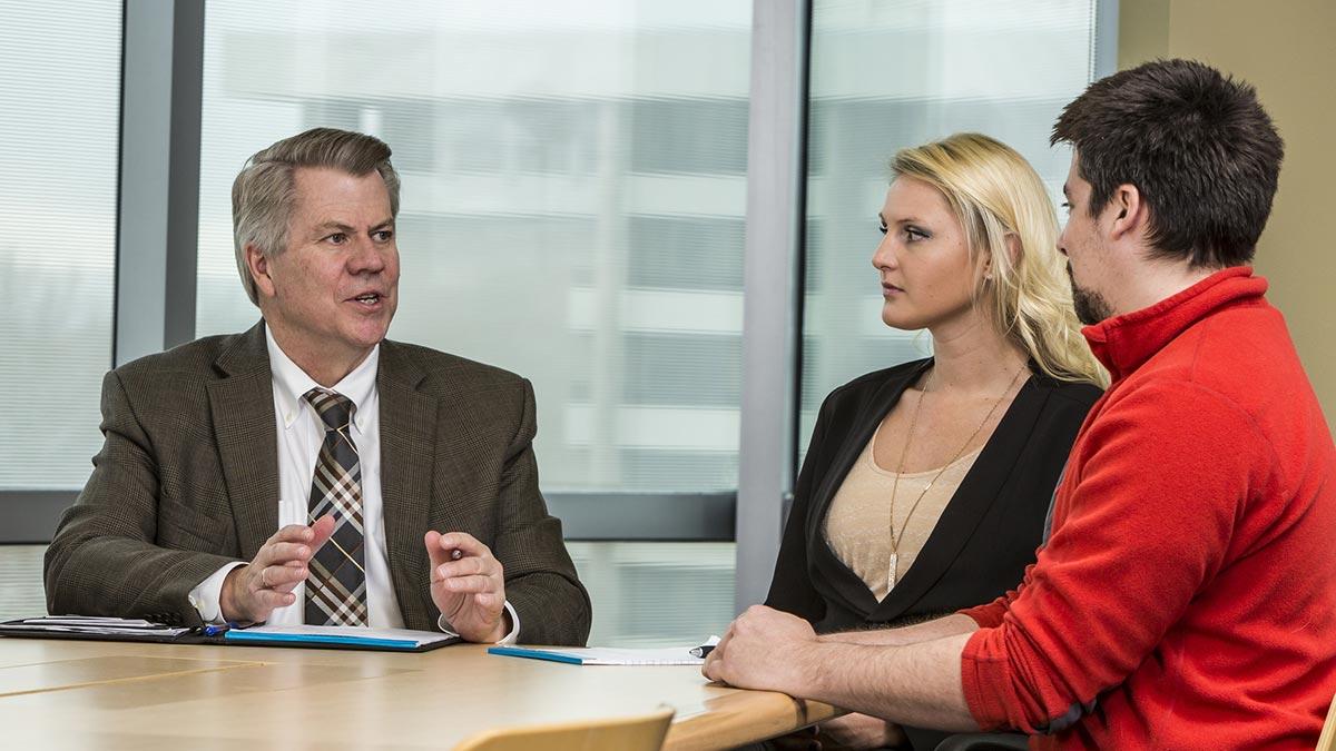 Three people sitting at a table in discussion.